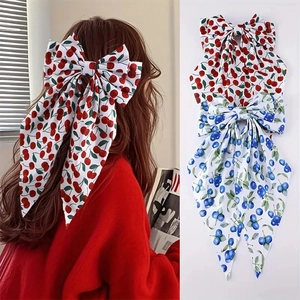 Detail view of long ribbon bow hair clips with cherry and blueberry fruit prints