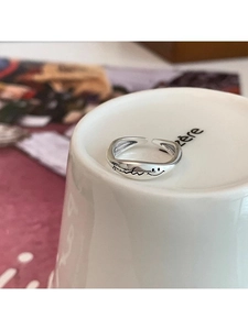 Detail of s925 silver smiley face open ring on white ceramic cup with artistic engraving