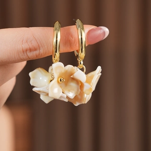 Detailed shot of vintage C-shaped gold hoop earrings with layered cream flower petals