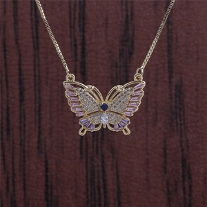Detailed close-up of golden butterfly necklace with pink and blue crystal zircon inlay