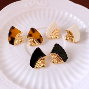Vue détaillée de boucles d'oreilles géométriques en résine avec texture éventail dorée