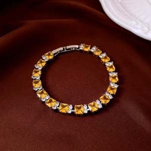Detail of elegant silver tennis bracelet with yellow and white stones on brown satin