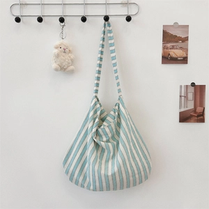 Detailed texture of striped canvas tote bag featuring a cute lamb plush keychain charm