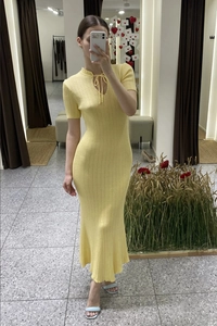 Dettaglio dell'abito in maglia giallo chiaro con scollo a goccia e trama a coste verticali