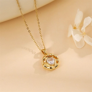 Macro shot of gold heart necklace with clear zircon stone and wave-textured pendant border