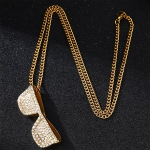 Golden iced-out sunglasses pendant necklace with micro-pave crystals on black background