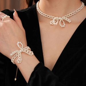 Details von elegantem Perlenschmuck-Set mit Schleifenmotiven an einem weiblichen Model