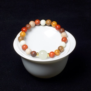 Macro shot of multi-color wooden beads bracelet with translucent green accents on white ceramic