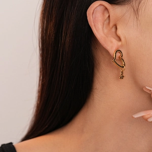 Detail of vintage gold heart earrings with black zircon and saturn pendant on model