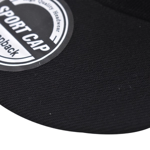 Close-up van een zwarte katoenen honkbalpet met fijne twill textuur en sport sticker detail