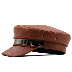 Macro detail of brown faux leather military hat with metal band and M logo