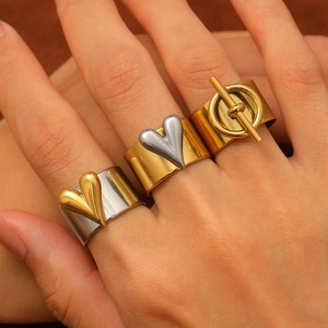 Detail of gold and silver stainless steel rings with toggle heart motifs worn on fingers