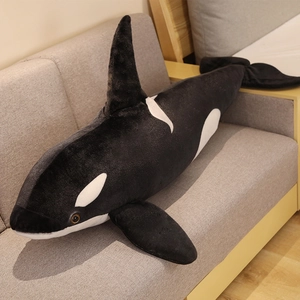 Detailed view of the soft black and white orca plush pillow on a cozy fabric sofa
