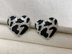 Detailed view of silver heart-shaped stud earrings featuring black leopard print texture