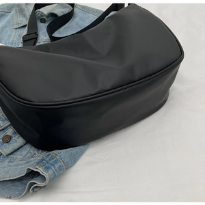 Close-up of a black matte crossbody bag placed on a blue denim jacket for daily style