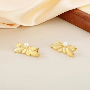 Detail of gold butterfly wing earrings with white pearl inlay on soft silk fabric