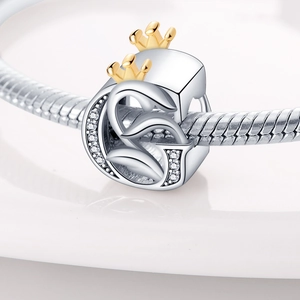 Macro detail of silver charm bead with golden crown, number 5 and sparkling crystals