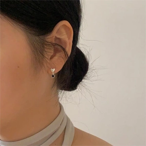 Detailed side view of a minimalist 925 silver heart earring with a black dangling element