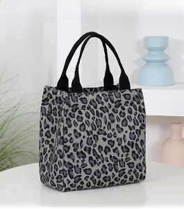 Detail view of the leopard print pattern and reinforced black handles on a tote bag