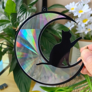 Macro detail of crescent moon and cat suncatcher with holographic prism rainbow effect
