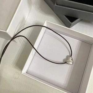 Minimalist silver heart pendant necklace with dark brown woven rope on white jewelry box