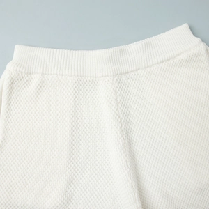 Close-up of ribbed elastic waistband on high-quality white knit shorts with textured fabric