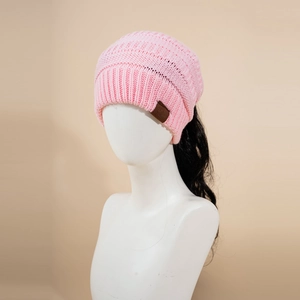 Detail showing the ponytail hole design and knitted texture of the pink winter beanie