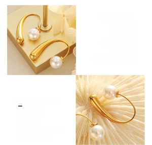 Macro detail of C-shaped titanium steel earrings with 18K gold plating and faux pearls