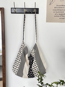 Hanging canvas tote bag with black and white polka dot patchwork on white wall