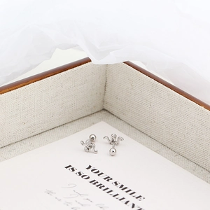 Detail shot of silver snake and crown earrings with diamond accents on a card