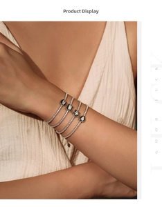 Detail of silver S925 tennis bracelets with geometric charms on a model's wrist