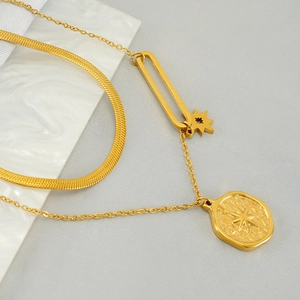 Vintage gold layered necklace featuring a flat snake chain and starburst oval pendant