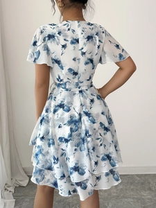 Vista posteriore di un vestito bianco a maniche corte con fiori blu e fiocco in vita