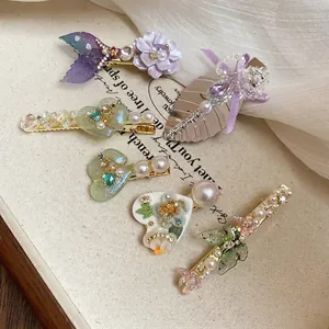 Lot de barrettes à fleurs et feuilles en strass avec perles et papillon sur tissu beige