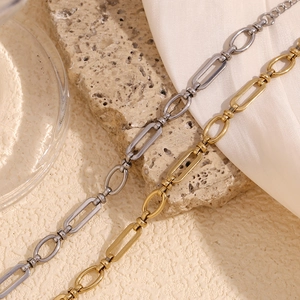 Detailed close-up of 14K gold and silver paperclip chain bracelets on stone texture