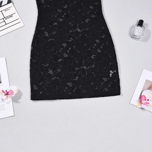 Detalle en plano de dobladillo de vestido de encaje negro Y2K con accesorios decorativos