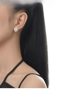 Close-up of pearl stud earring featuring intricate silver hollow mesh metal detailing