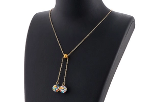 Detail of gold necklace with two sparkling colorful crystal spherical pendants on black bust