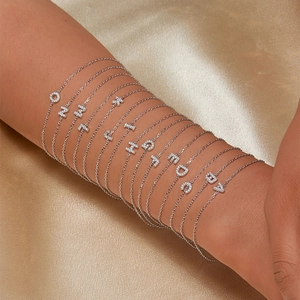 Close-up of 925 sterling silver alphabet bracelets with white zircon charms on gold satin