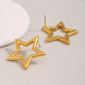 Detail of 18K gold plated hollow star stud earrings on a textured grey background