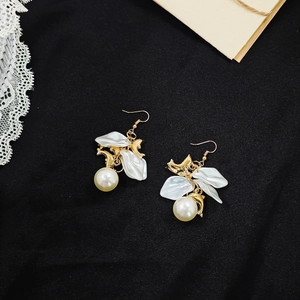 Detailed macro shot of French vintage earrings with white petals and pearls on black fabric