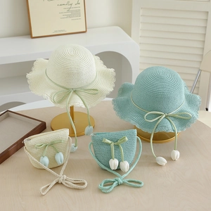 Detail of straw hat and bag set with ribbon bow and tulip charms in cream and blue