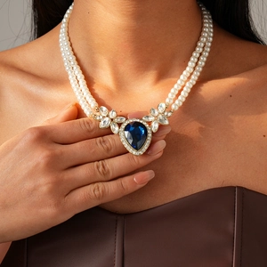 Détail d'un collier de perles double épaisseur avec pendentif goutte bleue et cristaux