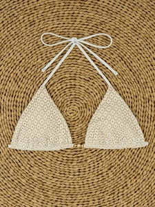 Close-up of white crochet bikini top with pearl detail and hollow knit pattern