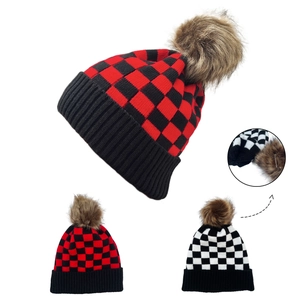 Detail of plaid knit beanie with fluffy faux fur pom-poms and ribbed cuff texture