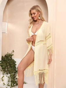 Detail of yellow crochet beach cover-up featuring fringe hem and bohemian hollow knit