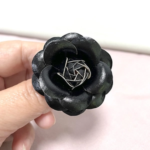 Macro shot of black PU leather camellia flower ring with silver wire center detail