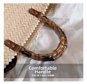 Detail of bamboo-style curved handle with gold rivets on a woven straw tote bag