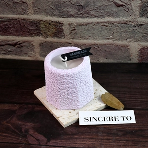 Detailed view of handmade light purple candle with textured surface and black label