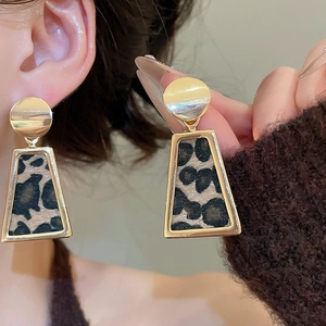 Close-up of vintage leopard print trapezoid earrings with golden frame and round studs